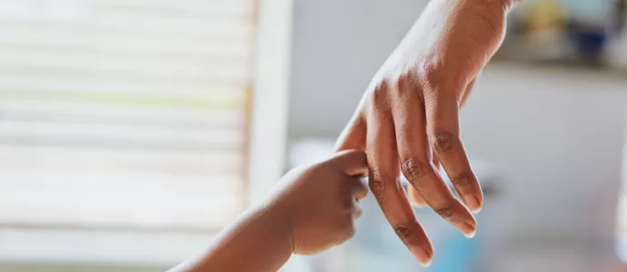 Child's hand holding adult's finger