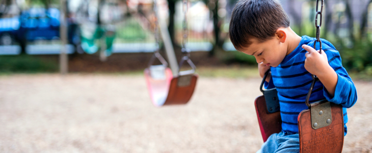 Sad child on swing dealing with child custody and domestic violence