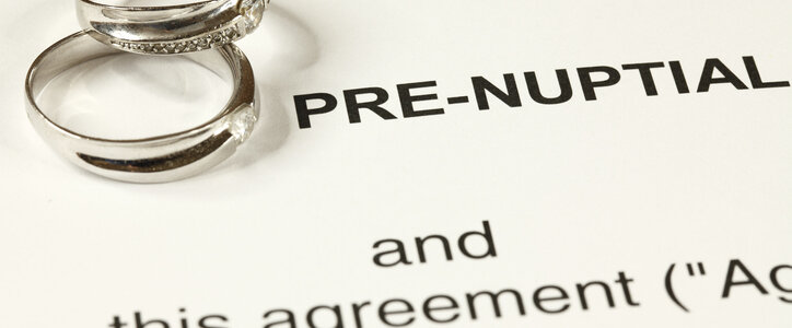 Prenuptial agreement document and two wedding rings on a table